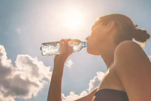 Hydration: The Secret Ingredient for a Toned Stomach and Enhanced Fitness 3 Image of woman drinking water to hydrate Wiltshire after run.